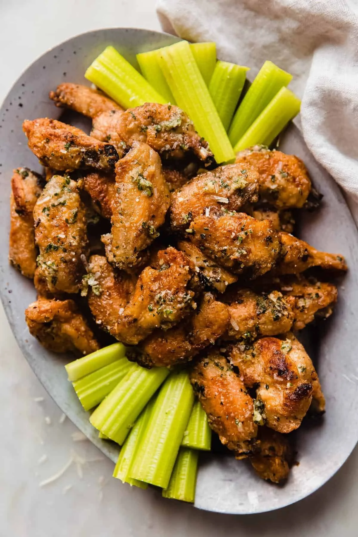 Crispy garlic-parmesan wings garnished with herbs on a plate